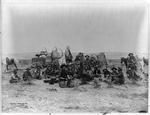 Cowboys sitting by supply wagons